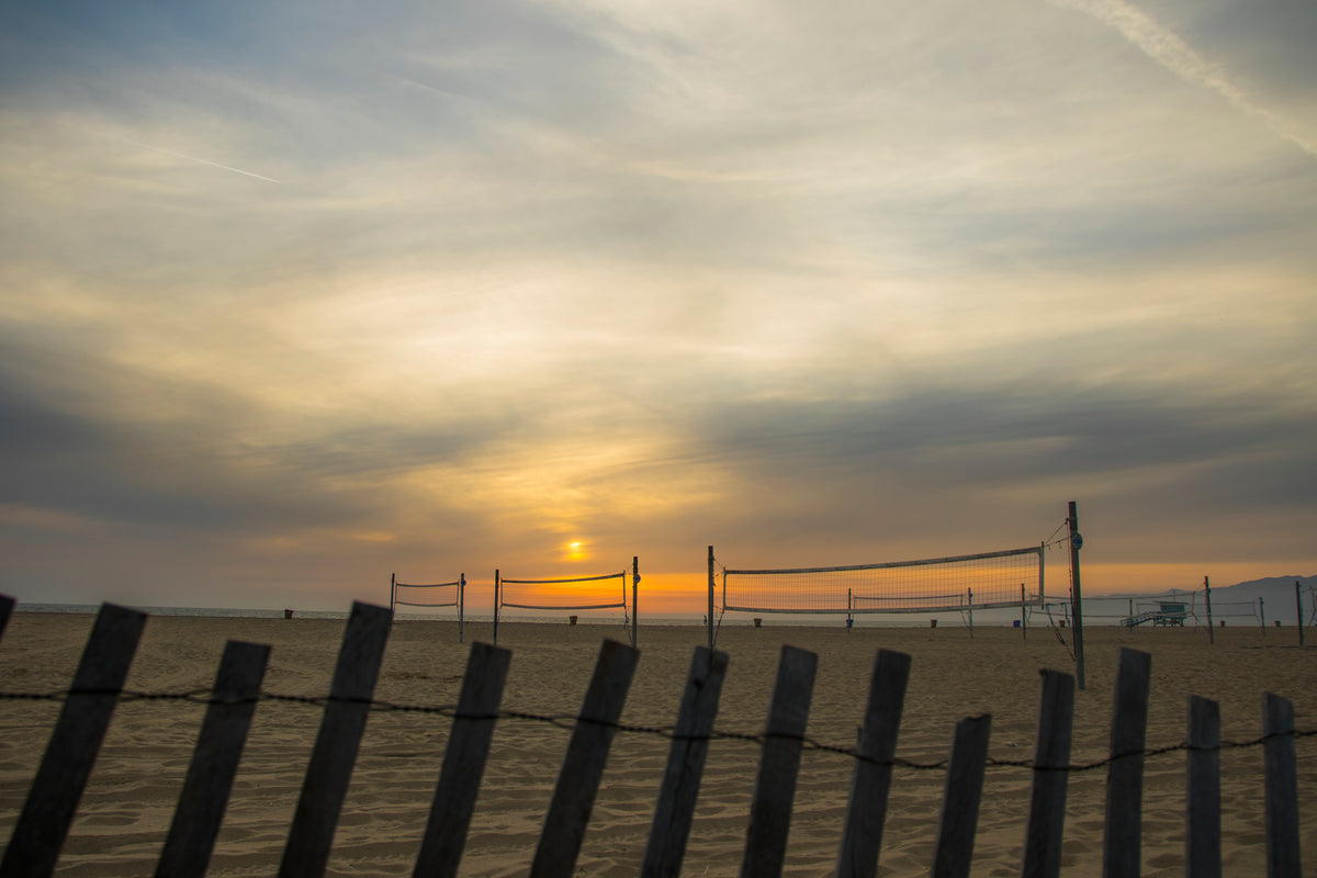 Auf dem Bild sind mehrere Beach-Volleyballfelder zu sehen. Im Hintergrund erkennt man das Meer und einen schönen Sonnenuntergang. Für einen Ausflug an einen solchen Ort ist Deine 720DGREE Flasche die beste Begleitung!