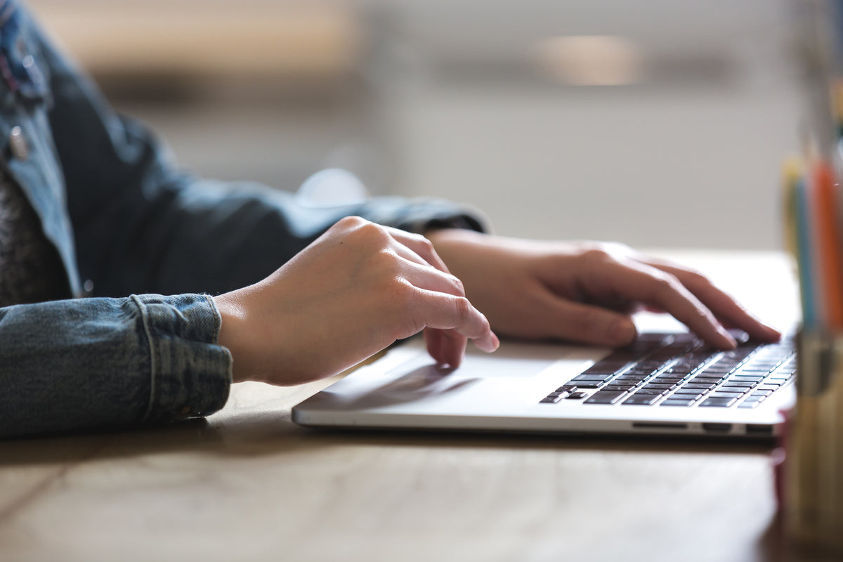 Co-Branding für Flaschen. Schreib uns einfach. Bild von einem Laptop. eine Person sitzt davor und schreibt etwas.