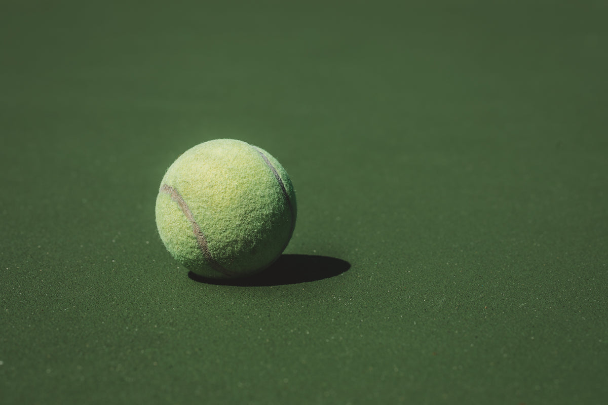 Auf einem Rasenplatz liegt ein Tennisball in der Sonne. In dieser Situation bist du mit unseren 720°DGREE Trinkflaschen perfekt ausgestattet.